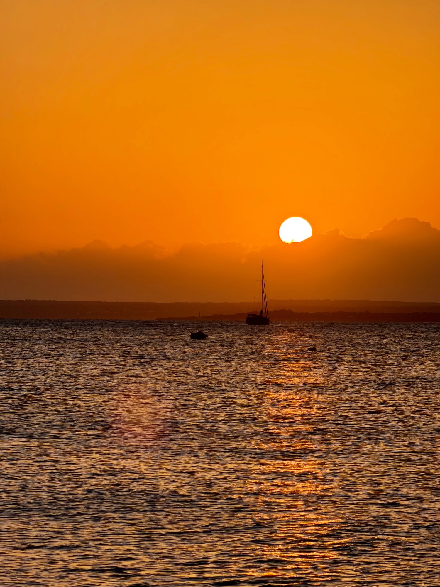Atardecer naranja sobre el mar con un velero